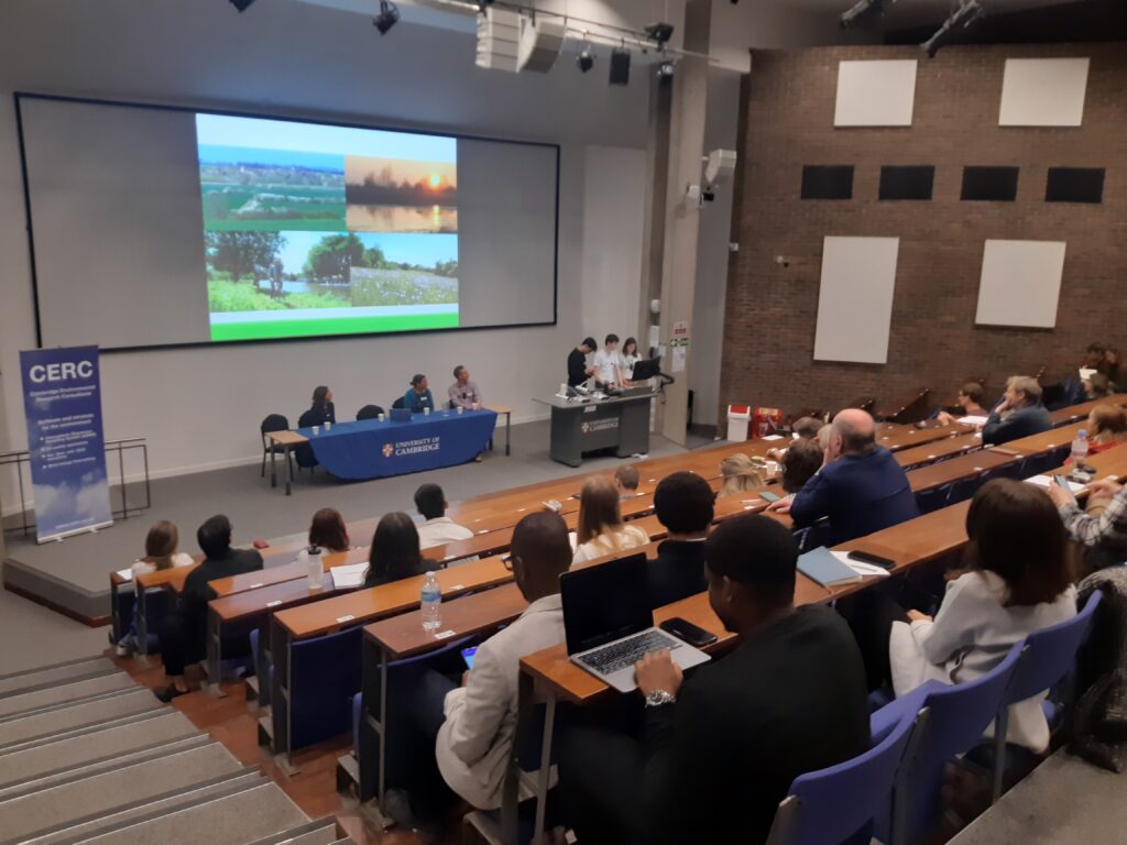 ID: a lecture theatre full of students, staff and members of the public in Cambridge.