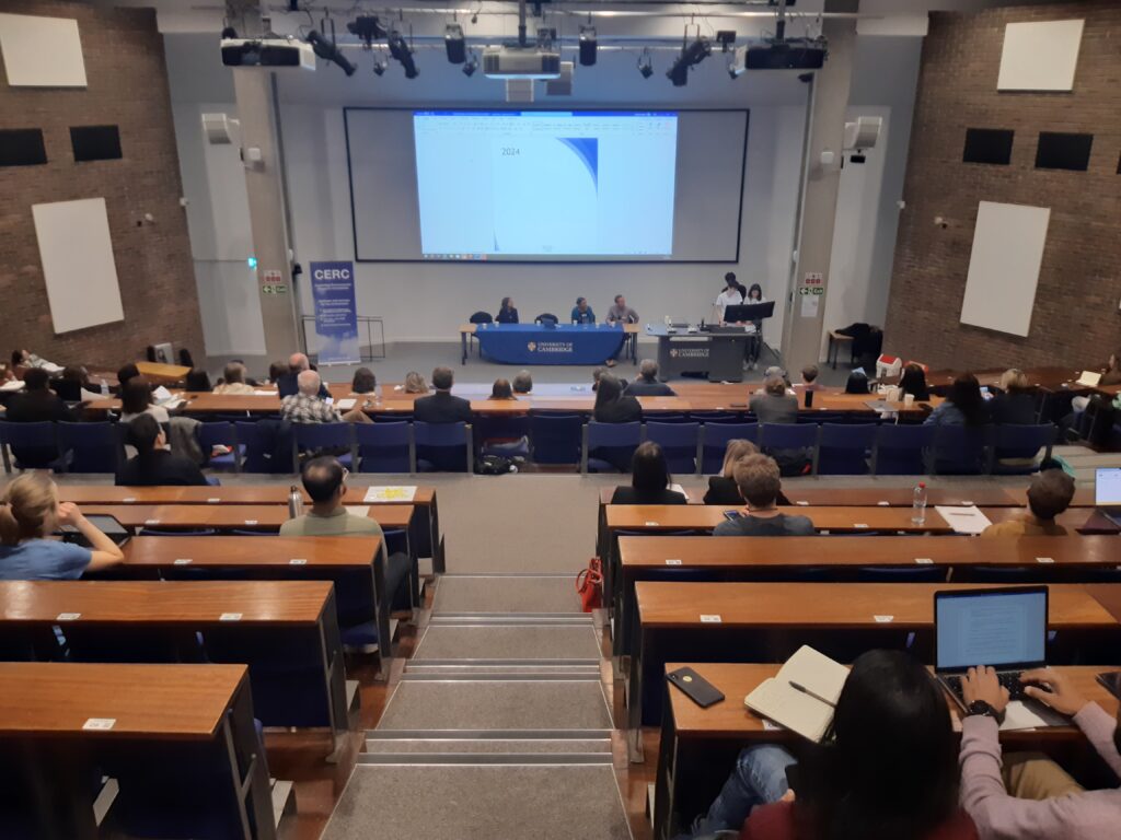 ID: a lecture theatre full of students, staff and members of the public in Cambridge.